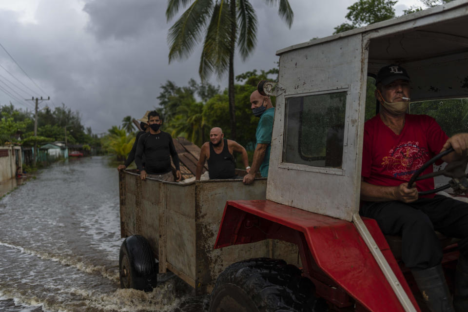 A man drives a tractor through a street flooded by rain brought on by Hurricane Ida, in Guanimar, Artemisa province, Cuba, Saturday Aug. 28, 2021. (AP Photo/Ramon Espinosa)
