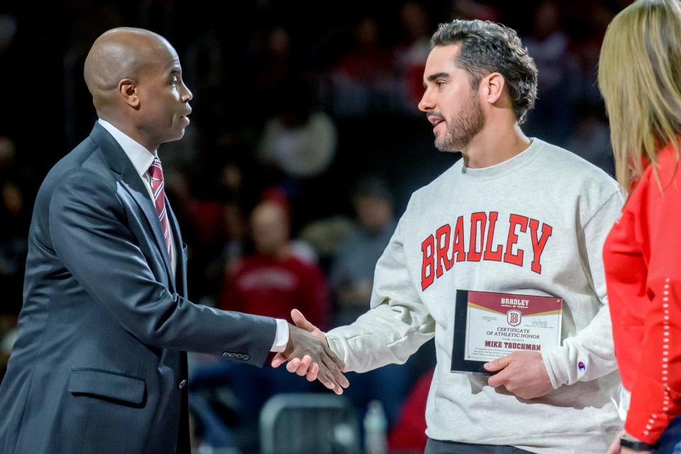 Bradley VP of Intercollegiate Athletics Chris Reynolds, left, shakes hands with popular Chicago Cubs outfielder and Bradley alum Mike Tauchman during a Bradley Hall of Fame ceremony at halftime of the Bradley-Belmont basketball game Saturday, Jan. 20, 2024 at Carver Arena in Peoria. The Braves routed the Bruins 95-72.