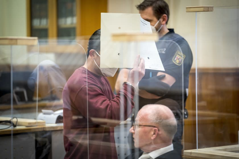 Syrian defendant Eyad Al-Gharib hides his face as he arrives to his hear his verdict in a court room in Koblenz, Germany, Wednesday, Feb. 24, 2021. A German court has convicted the former member of Syrian President Bashar Assad's secret police of facilitating the torture of prisoners in a landmark ruling that human rights campaigners hope will set a precedent for other cases. (Thomas Lohnes/Pool Photo via AP)