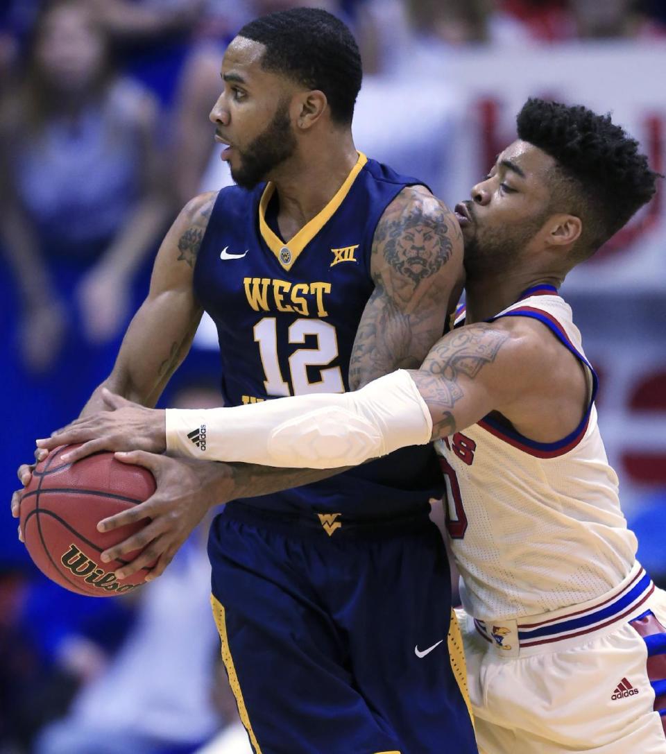 Kansas guard Frank Mason III (0) reaches around West Virginia guard Tarik Phillip (12) during the first half of an NCAA college basketball game in Lawrence, Kan., Monday, Feb. 13, 2017. (AP Photo/Orlin Wagner)