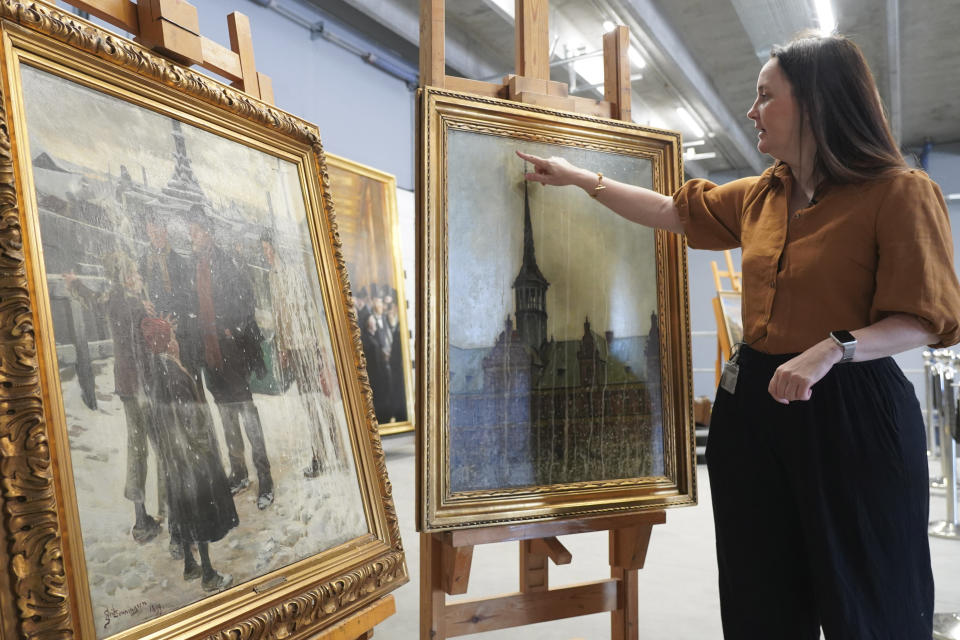 National Museum of Denmark paintings conservator Nina Wajnman points to a painting rescued from the fire at Denmark’s Old Stock Exchange building in mid-April, on display at the National Museum of Denmark’s warehouse in Vinge, Denmark, on Tuesday, June 4, 2024. Boersen, in Copenhagen, caught fire on April 16, 2024. More than 300 art objects were saved from the burning building. (AP Photo/James Brooks)