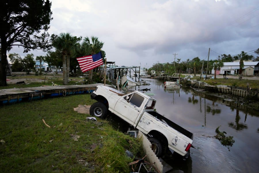 A pickup truck with an American flag tied to sits halfway into a canal in Horseshoe Beach, Fla., after the passage of Hurricane Idalia, Wednesday, Aug. 30, 2023. (AP Photo/Rebecca Blackwell)