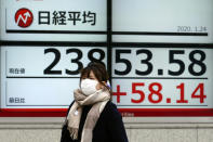 A woman walks past an electronic stock board showing Japan's Nikkei 225 index at a securities firm in Tokyo Friday, Jan. 24, 2020. Shares are mostly higher in quiet trading as China closes down for its week-long Lunar New Year festival. (AP Photo/Eugene Hoshiko)