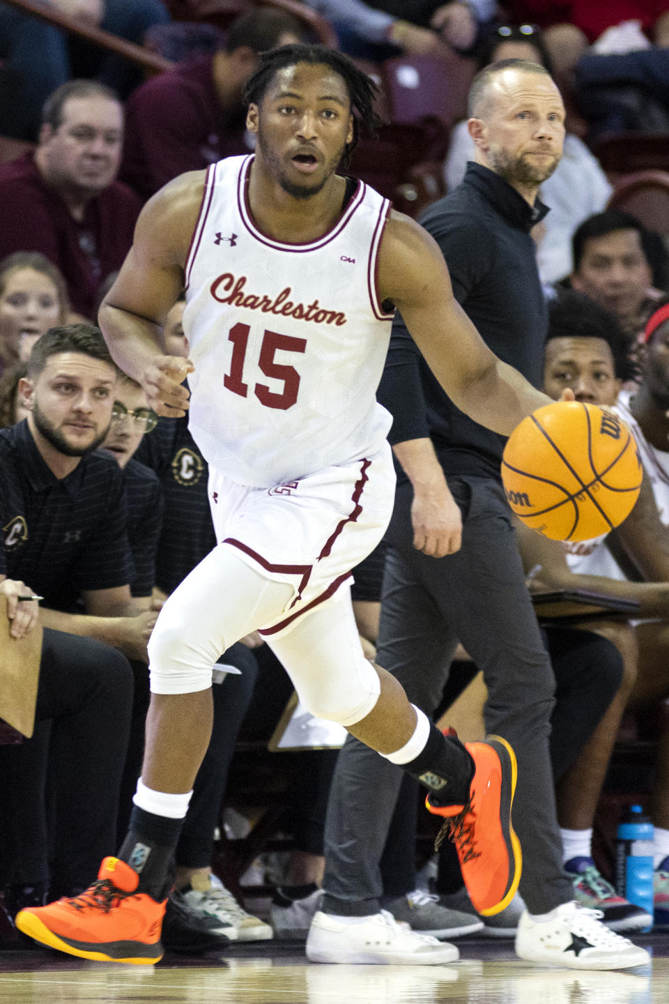 College of Charleston's Pat Robinson III (15) dribbles upcourt against Elon in the first half of an NCAA college basketball game in Charleston, S.C., Saturday, Jan. 14, 2023. College of Charleston head coach Pat Kelsey, right, looks on. (AP Photo/Mic Smith)