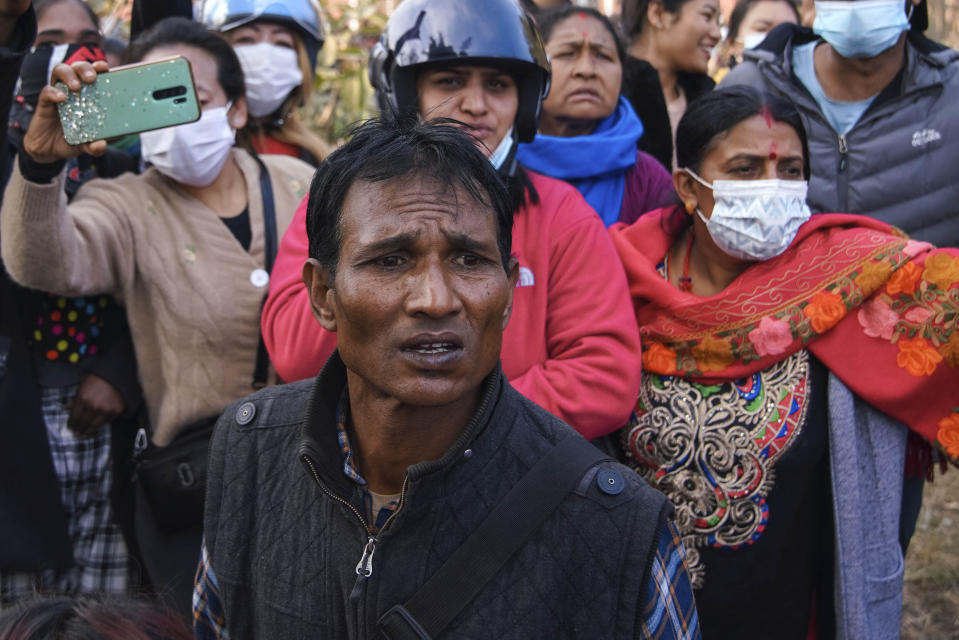 People watch rescuers work at the site of plane crash in Pokhara, Nepal, Sunday, Jan. 15, 2023. A plane making a 27-minute flight to a Nepal tourist town crashed into a gorge Sunday while attempting to land at a newly opened airport, killing at least 68 of the 72 people aboard. At least one witness reported hearing cries for help from within the fiery wreck, the country’s deadliest airplane accident in three decades. (AP Photo/Yunish Gurung)