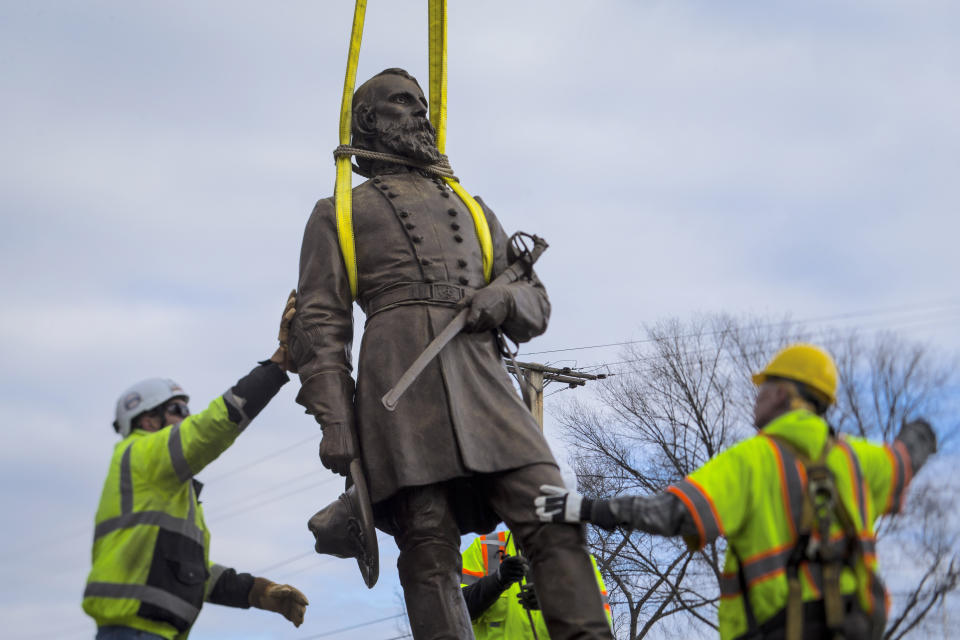 Workers begin to lay the bronze statue of Confederate General A.P. Hill onto a flatbed truck on Monday Dec. 12, 2022 in Richmond, Va. Workers are still planning to exhume the remains of General Hill which located inside the base of the statue. (AP Photo/John C. Clark)