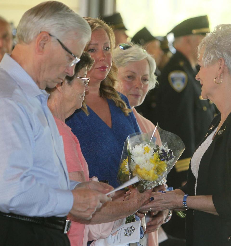 A member of the Akron FOP Auxiliary 1 presents flowers to the family of Akron Police Officer Justin R. Winebrenner, his uncle and aunt Charles and Janet Parsons, his fiancŽ Tiffany Miller and his aunt Joanne Winebrenner Escarcega during the Akron Police Memorial Day ceremony at the Fraternal Order of Police Akron Lodge 7 on Wednesday. Officer Winebrenner was shot and killed in 2014 during a struggle with an armed assailant. 
