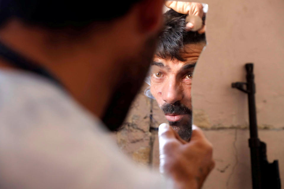 <p>A fighter of Syrian Democratic Forces fixes his hair using a broken mirror at the frontline in Raqqa, Syria, Oct. 6, 2017. (Photo: Erik De Castro/Reuters) </p>