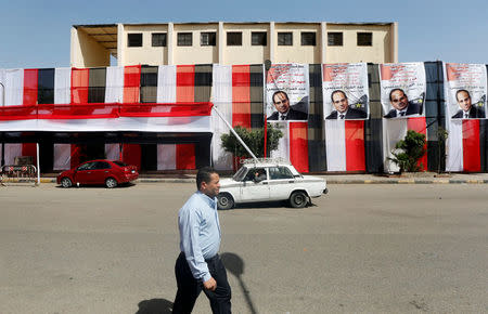 People walk in front of polling stations covered from outside by Egyptian flags and posters of Egypt's President Abdel Fattah al-Sisi during the preparations for tomorrow's presidential election in Cairo, Egypt, March 25, 2018. REUTERS/Amr Abdallah Dalsh