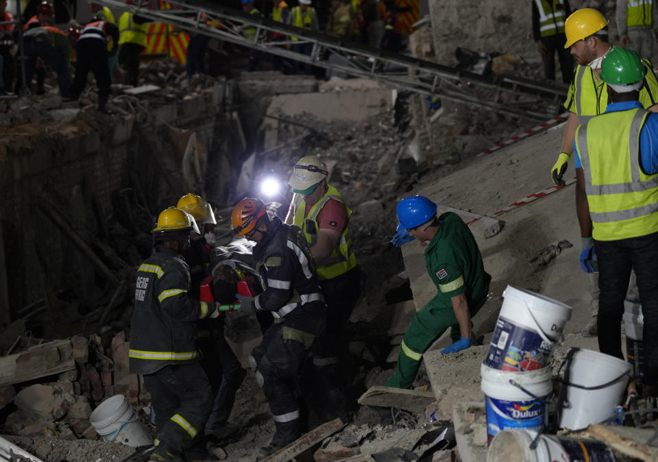 A survivor is carried on a stretcher at the scene of a building collapse in the city of George, about 400 kilometers (250 miles) east of Cape Town, South Africa, Tuesday, May 7, 2024. Rescue teams trying to find dozens of construction workers missing since a multi-story apartment complex collapsed in a coastal city in South Africa have made contact with 11 people buried alive beneath the mangled wreckage, authorities said Tuesday. (AP Photo/Nardus Engelbrecht)