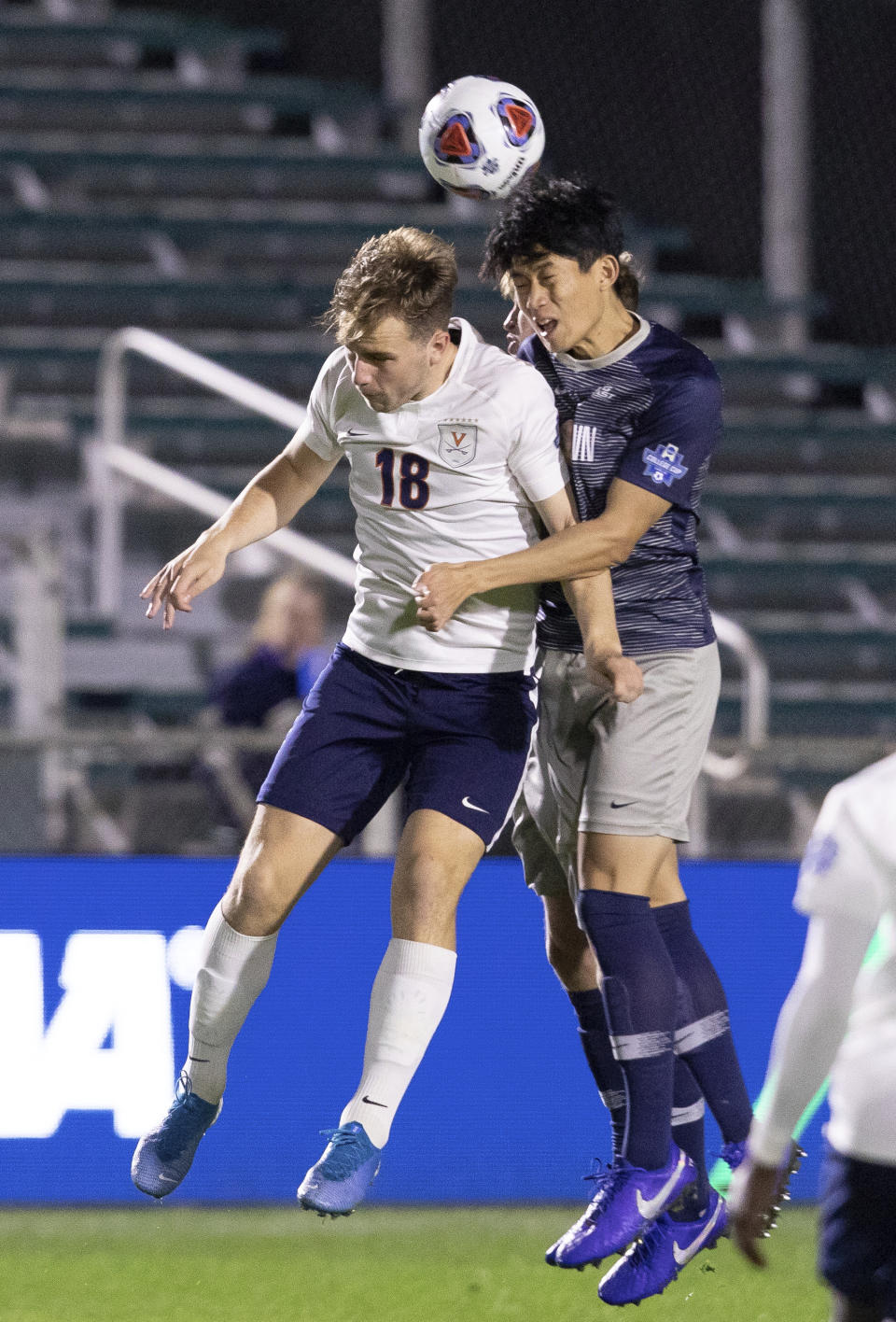 Virginia's Axel Gunnarsson (18) and Georgetown's Daniel Wu, right, jump for a ball during the first half of the NCAA college Soccer Championship in Cary, N.C., Sunday, Dec. 15, 2019. (AP Photo/Ben McKeown)