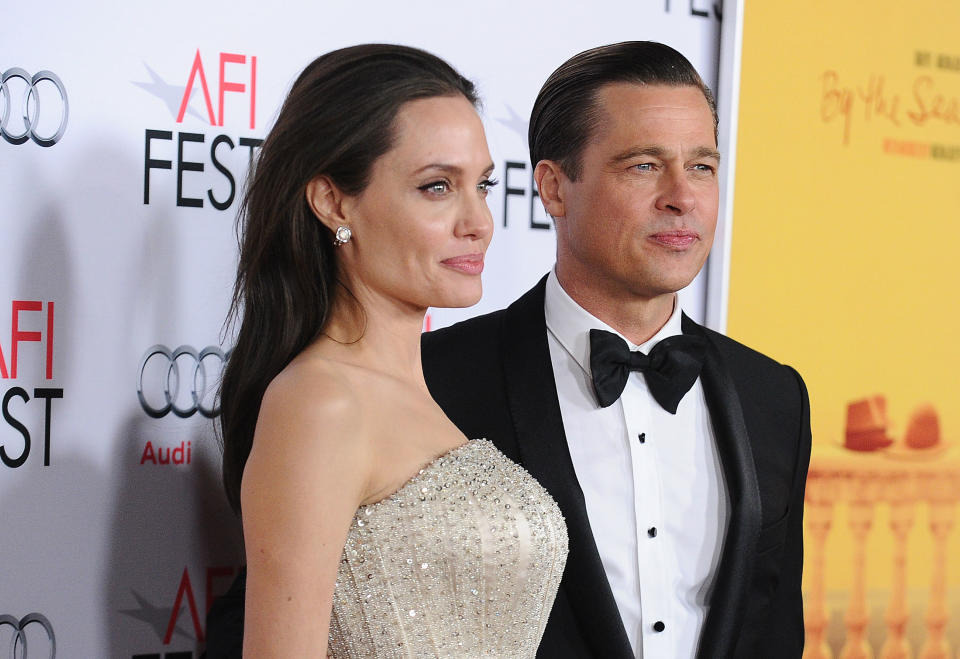 Angelina Jolie in a strapless gown and Brad Pitt in a tuxedo pose together at the AFI Fest