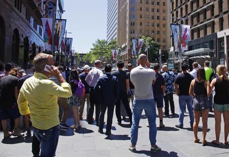 People standing behind a police cordon look towards Lindt cafe in Martin Place, where hostages are being held, in central Sydney December 15, 2014. REUTERS/David Gray