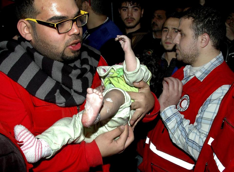 FILE - In this Monday Feb. 10, 2014 file photo, released by the Syrian official news agency SANA, a Syrian Arab Red Crescent member carries a baby to a bus to evacuate from the battleground city of Homs, Syria. Weeping children begged for food in the streets and women picked grass growing in the cracks of the sidewalks to eat as hunger gripped residents of rebel-held neighborhoods of the Syrian city of Homs blockaded for nearly two years by the military, according to a rare first-hand account by a man evacuated during a truce this week. (AP Photo/SANA, File)