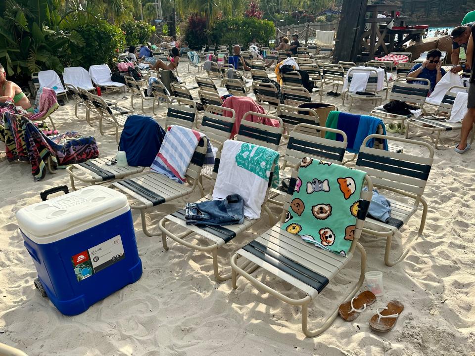 rows of beach chairs with towels on them in a sandy area