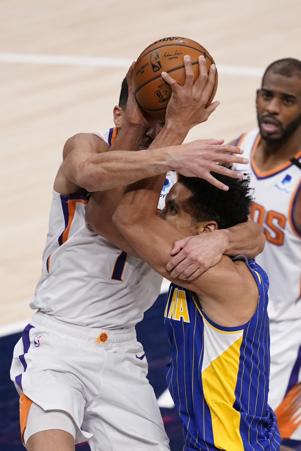 Indiana Pacers' Malcolm Brogdon (7) is fouled by Phoenix Suns' Devin Booker (1) as he goes up to shoot during the second half of an NBA basketball game, Saturday, Jan. 9, 2021, in Indianapolis. (AP Photo/Darron Cummings)