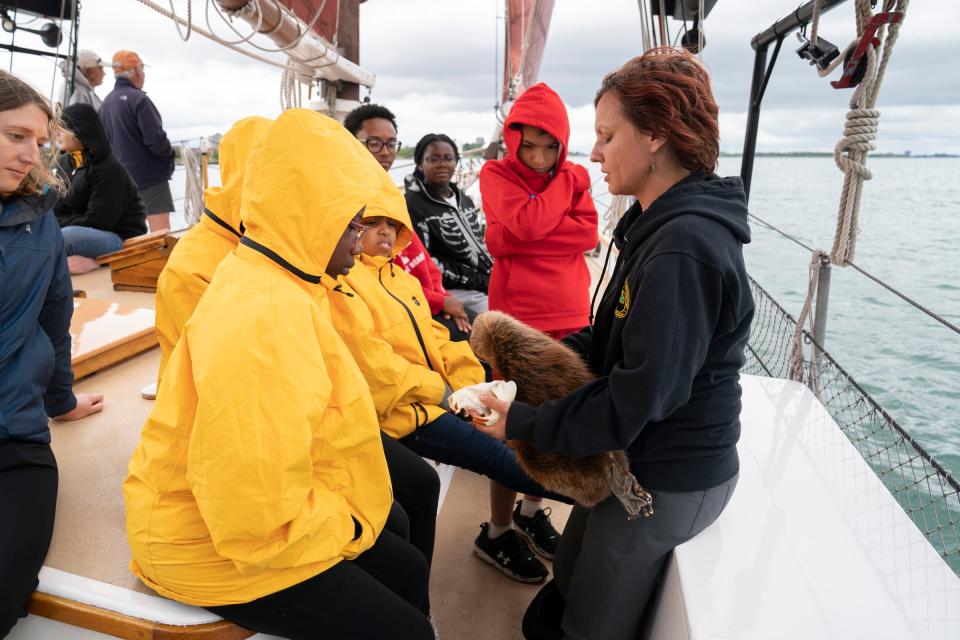 DNR educator Natalie Cypher, 36, of New Boston, right, shows a beaver pelt to educate students of Accent Pontiac Youth what species have returned to the area while sailing on the Inland Seas schooner around the Detroit River on Aug. 7, 2023. The Detroit River Skiff and Schooner program takes youths from around metro Detroit and educates them on area history, ecology, culture, and the love of sailing.