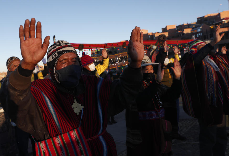 Los indígenas aymaras con máscaras faciales de protección levantan sus manos ante los primeros rayos de sol durante un ritual de año nuevo en el Mirador Jach'a Apacheta de Munaypata, en La Paz, Bolivia, el domingo 21 de junio de 2020. Las comunidades indígenas aymaras celebran el Año Nuevo Andino 5.528 en medio de la pandemia del nuevo coronavirus. (Foto AP/Juan Karita)