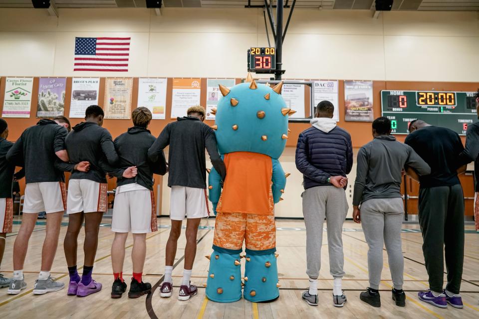 Members of the Copper Mountain College basketball team pose with their mascot, the Copper Mountain Fighting Cacti, on their home court.