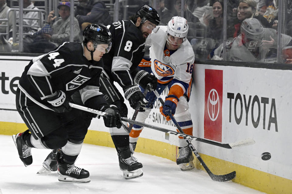 New York Islanders left wing Pierre Engvall (18) passes the puck away from Los Angeles Kings defensemen Mikey Anderson (44) and Drew Doughty (8) during the first period of an NHL hockey game in Los Angeles, Monday, March 11, 2024. (AP Photo/Alex Gallardo)