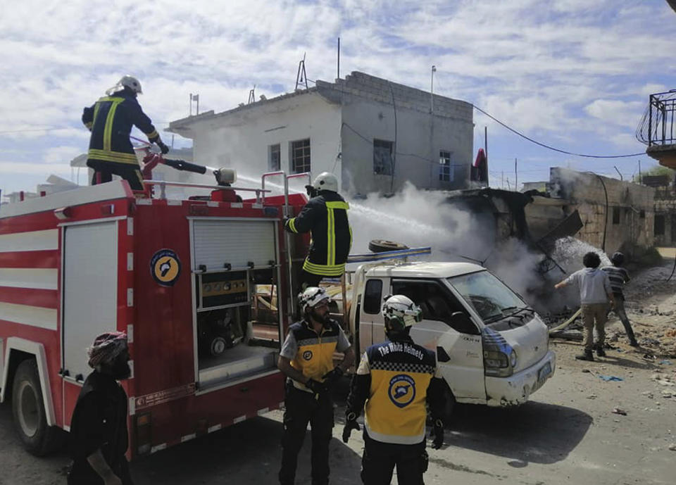 This photo provided by the Syrian Civil Defense White Helmets, which has been authenticated based on its contents and other AP reporting, shows a civil defense worker extinguishing damaged shops after shelling hit a street in the town of Ehssem, southern Idlib, Syria, Friday, May 3, 2019. Syrian state media and activists are reporting a wave of government and Russian airstrikes, including indiscriminate barrel bombs, on the rebel-held enclave in northwestern Syria where a seven-month truce is teetering under a violent escalation. (Syrian Civil Defense White Helmets via AP)