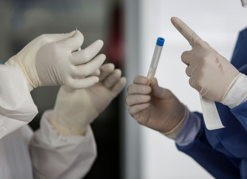 Healthcare workers handle a swab sample from a patient at a drive-thru testing site for the coronavirus disease (COVID-19) in Monterrey