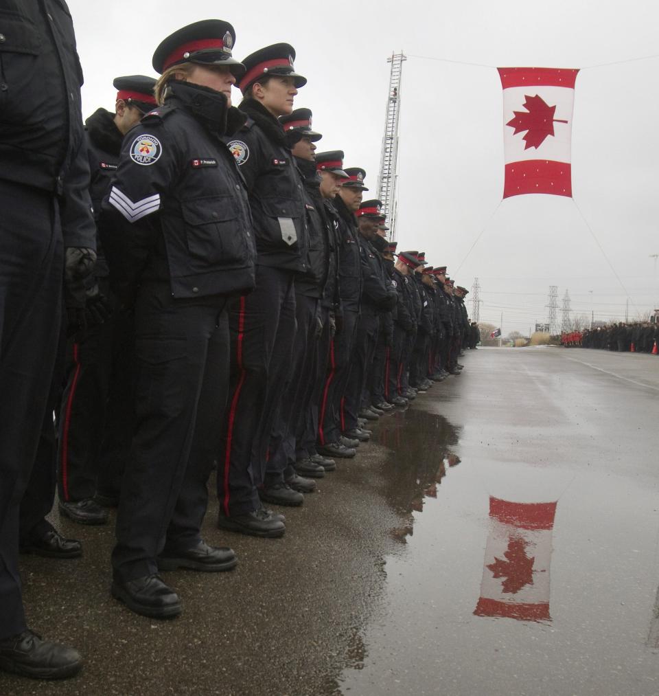 Police officers line the road while waiting for the hearse to arrive at the public memorial for police constable John Zivcic in Toronto