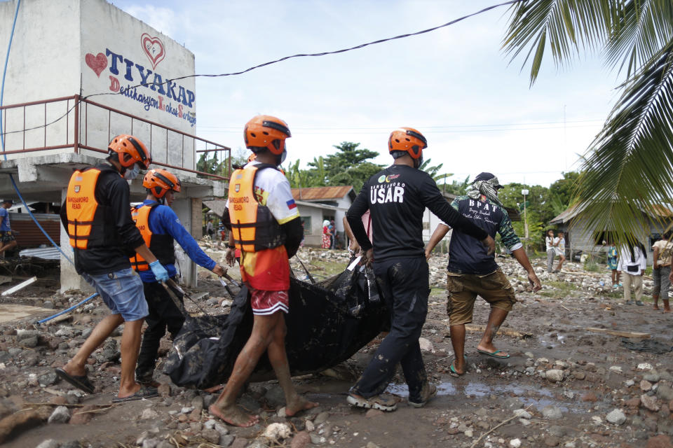 Rescuers carry a body which they retrieved after Tropical Storm Nalgae hit Maguindanao's Datu Odin Sinsuat town, southern Philippines on Saturday Oct. 29, 2022. Flash floods and landslides set off by torrential rains left dozens of people dead, including in a hard-hit southern Philippine province, where many villagers are feared missing and buried in a deluge of rainwater, mud, rocks and trees, officials said Saturday. (AP Photo)