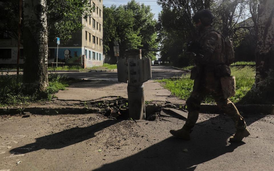 A Ukrainian soldier walks past a part of a rocket near the front line in the city of Severodonetsk, in the Luhansk region of Ukraine, on June 2, 2022, where heavy fighting took place in the last few days -  Shutterstock