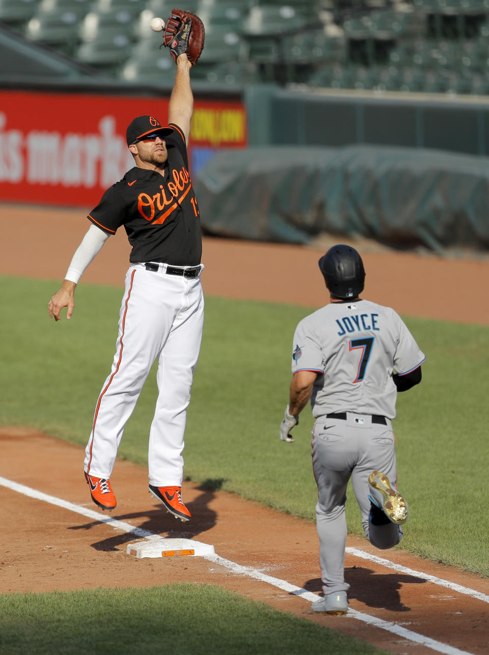 Baltimore Orioles first baseman Chris Davis, left, is unable to catch a high throw from starting pitcher Alex Cobb, not visible, on a dribbler hit by Miami Marlins' Matt Joyce (7) during the second inning in game one of a baseball double-header, Wednesday, Aug. 5, 2020, in Baltimore. (AP Photo/Julio Cortez)