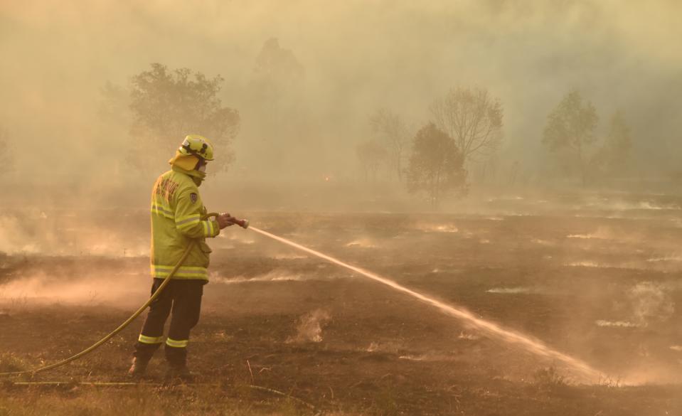 A firefighter defends a property from a bushfire at Hillville near Taree, 350km north of Sydney on November 12, 2019. - A state of emergency was declared on November 11 and residents in the Sydney area were warned of "catastrophic" fire danger as Australia prepared for a fresh wave of deadly bushfires that have ravaged the drought-stricken east of the country. (Photo by PETER PARKS / AFP) (Photo by PETER PARKS/AFP via Getty Images)
