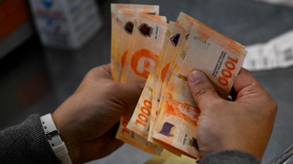 A man holding peso bills