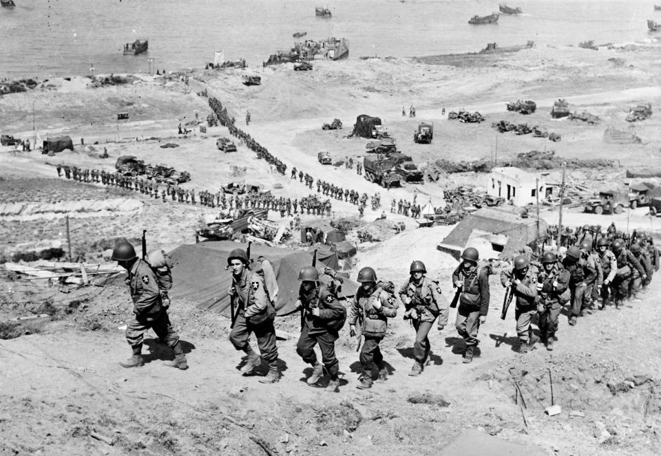 US soldiers march up a hill after the D-Day landings in 1944