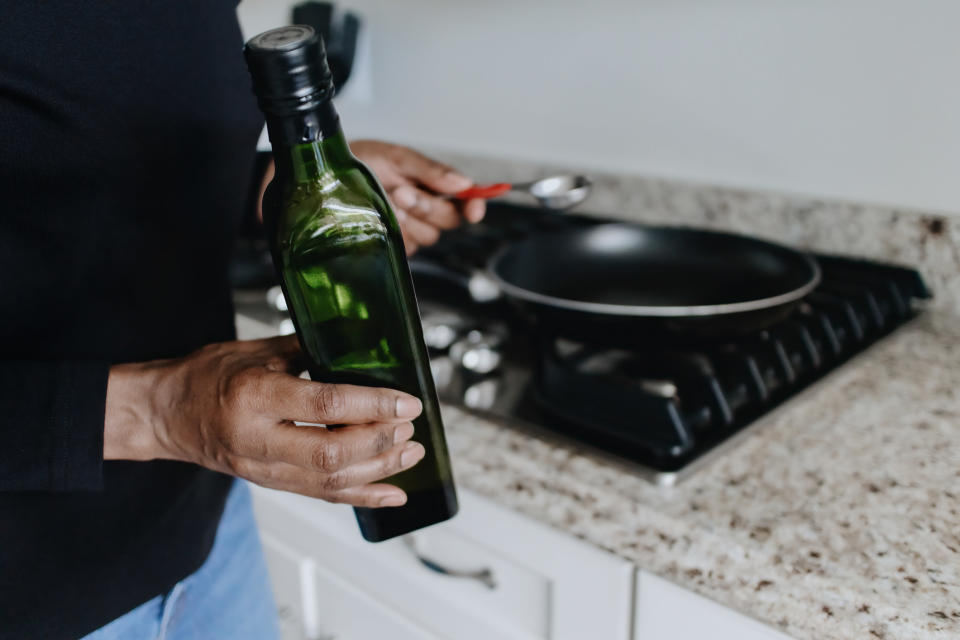 someone holding a bottle of olive oil