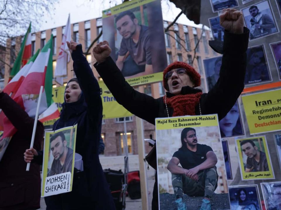 Protesters in Berlin on Dec. 12 wear portraits of Majid Reza Rahnavard, 23, and Mohsen Shekari, 23, both of whom were recently executed by Iranian authorities. (Sean Gallup/Getty Images - image credit)