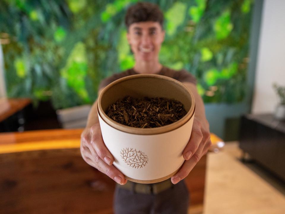 Katrina Spade, CEO of Recompose, holds up a put containing soil made from the decomposition process.