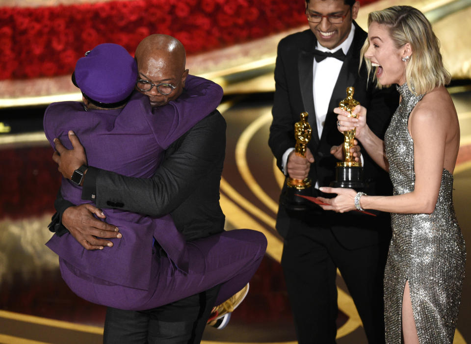 Spike Lee, winner of the award for best adapted screenplay for "BlacKkKlansman" jumps into the arms of presenter Samuel L. Jackson as fellow presenter Brie Larson, right, looks on, at the Oscars in Los Angeles on Feb. 24, 2019. It was the first Oscar awarded to the veteran filmmaker. (Photo by Chris Pizzello/Invision/AP)