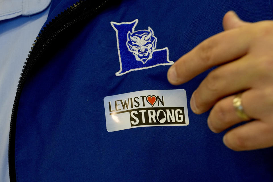 School Superintendent Jake Langlais applies a Lewiston Strong sticker to his jacket as high school students return to school for the first time since the shootings that claimed 18 lives in their community, Tuesday, Oct. 31, 2023, in Lewiston, Maine. (AP Photo/Matt York)