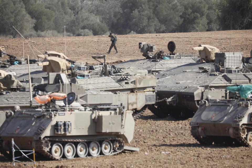 An Israeli soldier walks past military vehicles in a gathering point near the Israel-Gaza Border, Thursday, Nov. 14, 2019. Israel and the militant Islamic Jihad group in Gaza reached a cease-fire on Thursday to end the heaviest Gaza fighting in months. (AP Photo/Ariel Schalit)