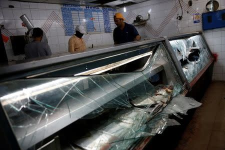 Men stand next to broken refrigerators, after a butcher's stall was looted in the slum of Petare in Caracas, Venezuela June 10, 2016. REUTERS/Carlos Garcia Rawlins/File Photo