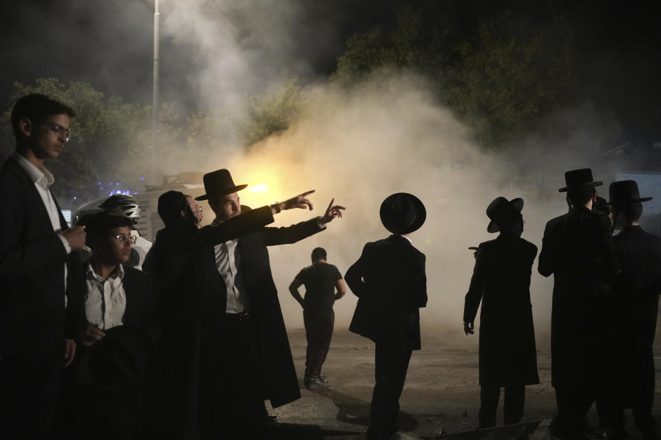 Ultra-Orthodox Jewish men inspect a damaged road after it was hit by a rocket fired from the Gaza Strip, in the West Bank Jewish settlement of Beitar Illit, Monday, Oct. 9, 2023. (AP Photo/Maya Alleruzzo)