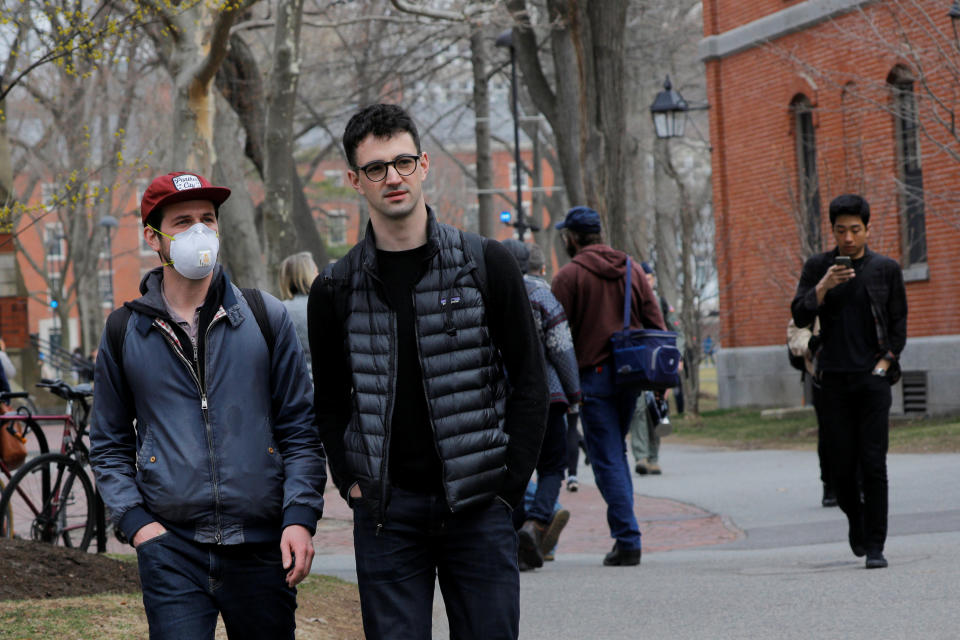 A student wearing a mask, because his cancer treatment has left him immunosuppressed and vulnerable to diseases such as the coronavirus, walks through the Yard at Harvard University, after the school asked its students not to return to campus after Spring Break and said it would move to virtual instruction for graduate and undergraduate classes, in Cambridge, Massachusetts, U.S., March 10, 2020.   REUTERS/Brian Snyder