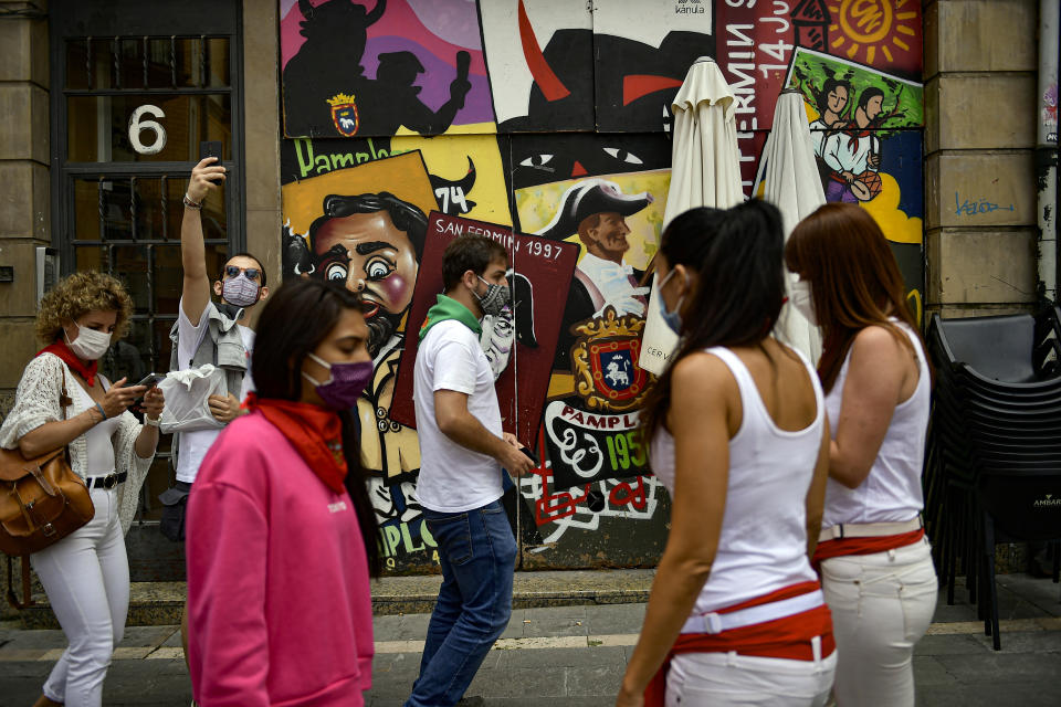 Residents, wearing white clothes and traditional red scarves, take to the streets on the day the ''txupinazo'' would usually take place to start the famous San Fermin festival, which was due canceled this year by the conoravirus, in Pamplona, northern Spain, Monday, July 6, 2020. (AP Photo/Alvaro Barrientos)