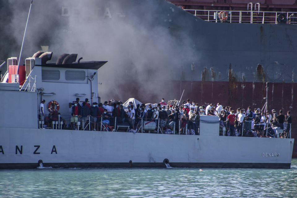 FILE - In this file photo taken on July 27, 2020, migrants arrive in Porto Empedocle, Sicily, aboard two military ships after being transferred from the island of Lampedusa. Sicily's governor has ordered all migrants to be transferred from the island by Monday, part of push-back by Italian regions alarmed by last week's surge in COVID-19 cases. On Saturday, Italy registered 1,071 new cases, the highest daily number since mid-May, and only weeks after the nation had seen the number of day-to-day new infections plunge to about 200. (Fabio Peonia/LaPresse via AP)