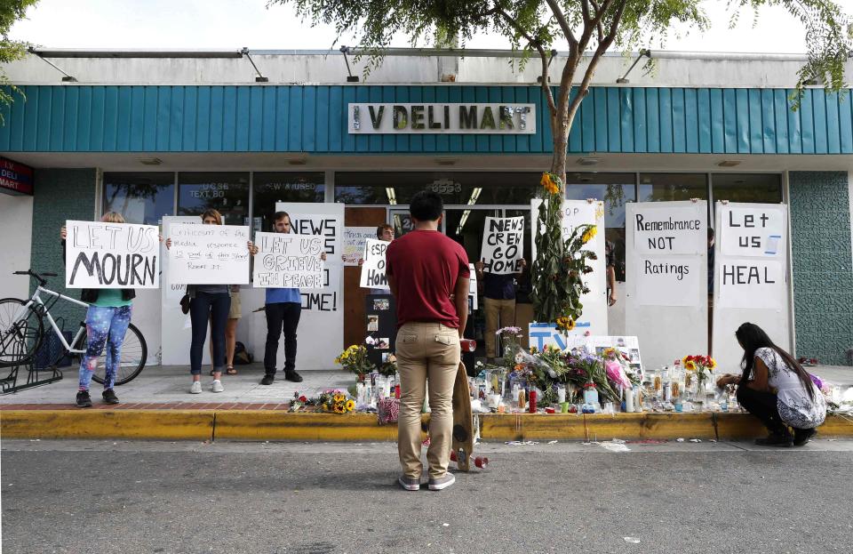 People protest the presence of news crews as a man stands in front of a makeshift shrine for 20-year-old UCSB student Christopher Michael-Martinez outside a deli that was one of nine crime scenes after series of drive-by shootings that left 7 people dead in the Isla Vista neighborhood of Santa Barbara, California May 26, 2014. Twenty-two year old Elliot Rodger killed six people before taking his own life in a rampage through a California college town shortly after he posted a threatening video railing against women, police said on Saturday. REUTERS/Lucy Nicholson (UNITED STATES - Tags: CRIME LAW CIVIL UNREST)