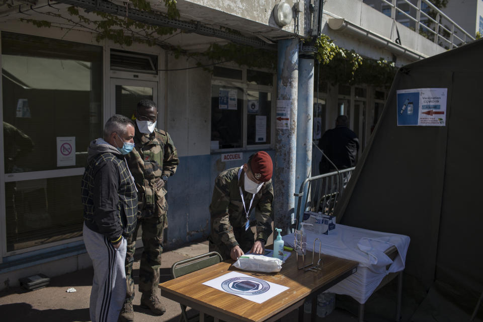 A French soldier receives people at a vaccination center set up at the Laveran Military Hospital in Marseille, southern France, Wednesday, April 7, 2021. Seven military hospitals also opened vaccination centers on Tuesday, operated by military and civilian staff, in an effort to inject up to 50,000 doses per week, the defense ministry said. (AP Photo/Daniel Cole)