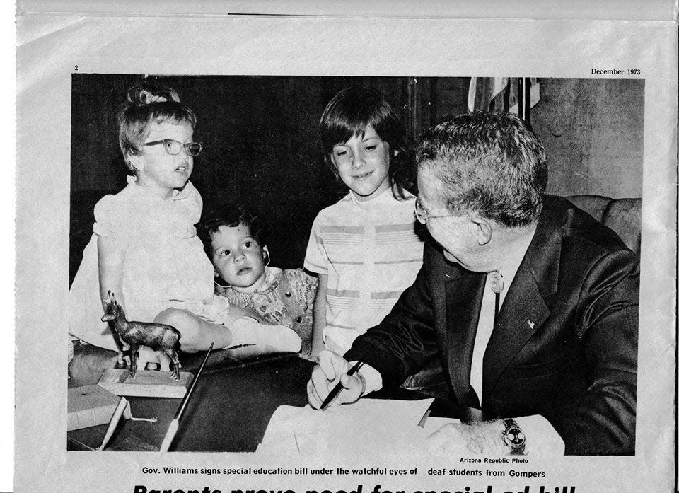 Diane Bolles (left) daughter of Arizona Republic reporter Don Bolles, watches as Arizona Gov. Jack Williams signs a bill that would move special education services into public schools. Don Bolles testified in favor of the bill on behalf of his daughter, who experienced hearing loss.