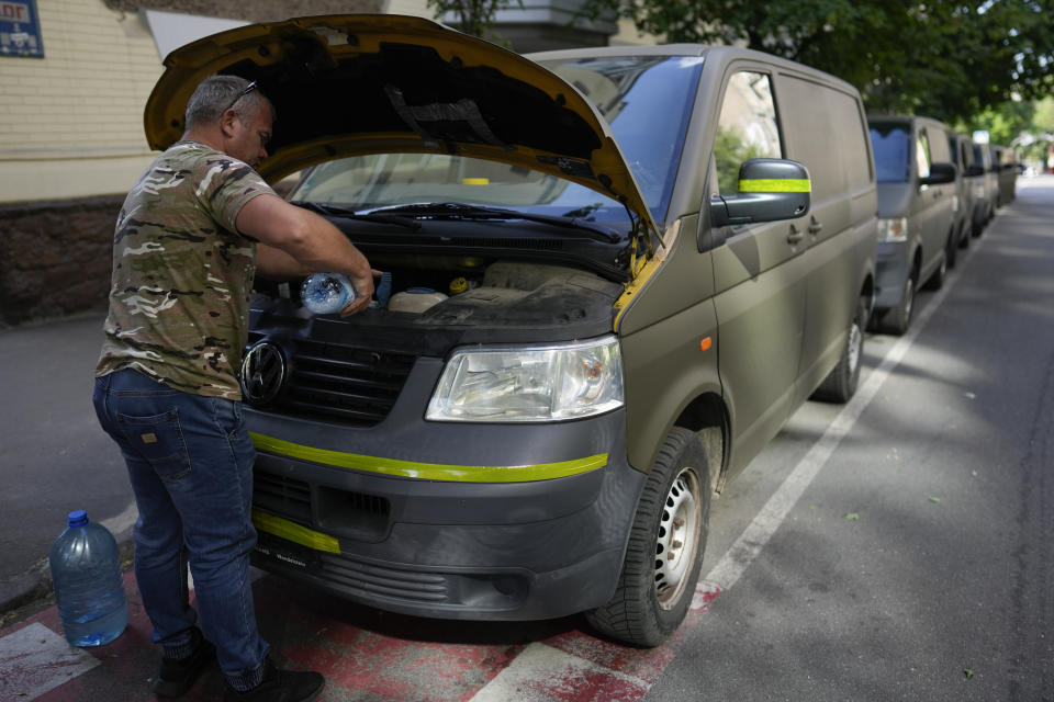 A volunteer puts water to a van motor before heading to delivered goods to soldiers fighting on the eastern and southern fronts, dispatched from an NGO storage center in Kyiv, Ukraine, Monday, June 13, 2022. In the war in Ukraine, troops on both sides are getting supplies from crowd-funders. On the Ukrainian side, the self-starting networks of donors and volunteers are particularly large, spontaneous and well-oiled. At a critical juncture of the invasion, their deliveries of drones, high-tech optical gear, vehicles and other equipment are keeping Ukraine in the fight against its better-supplied aggressor. (AP Photo/Natacha Pisarenko)