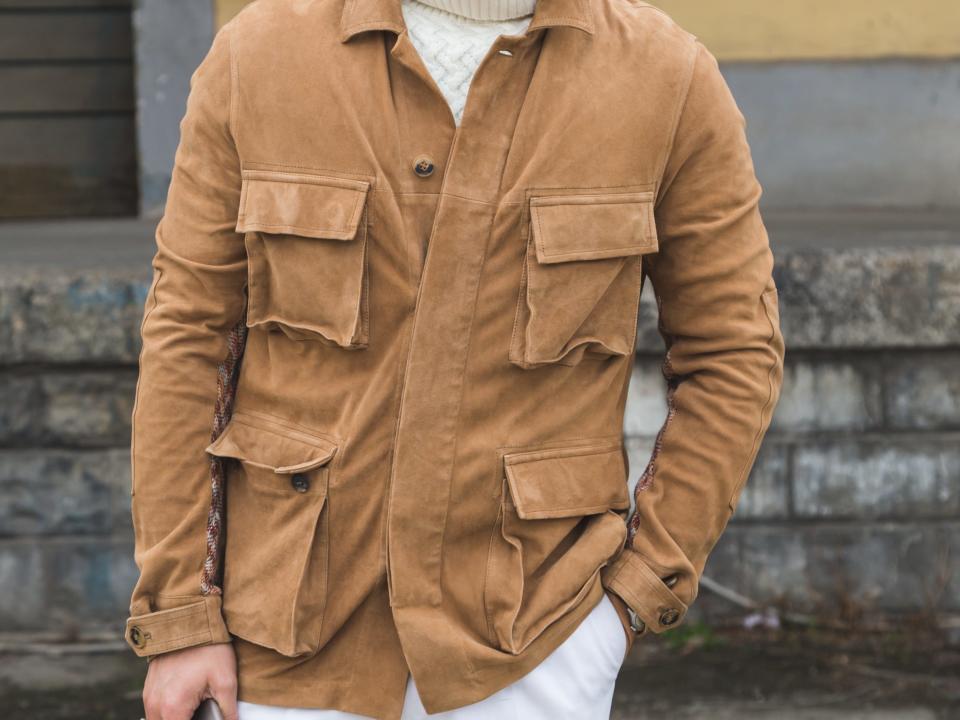 person wearing cream turtleneck sweater and white pants with tan jacket with cargo pockets