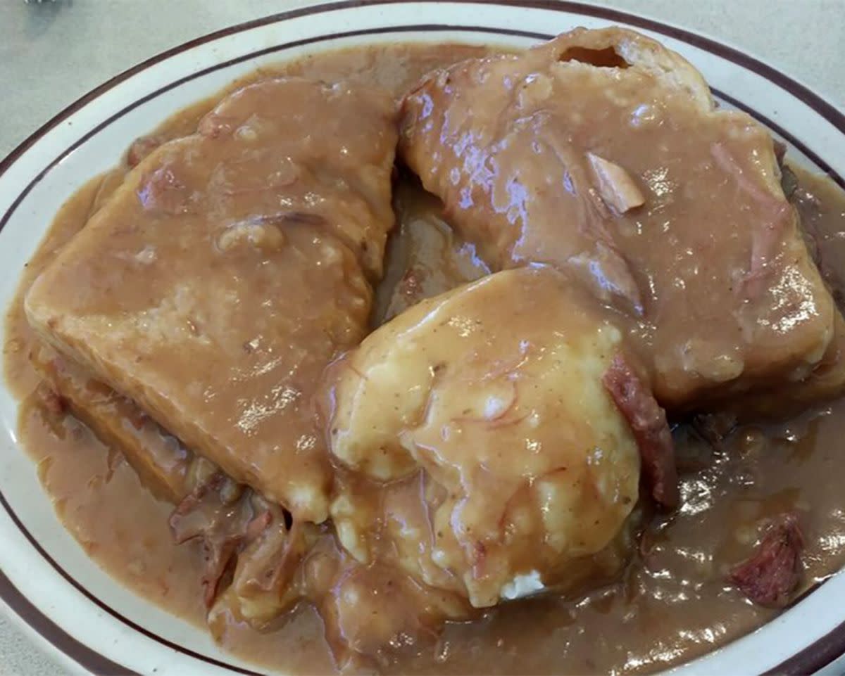 Hot Beef Commercial Sandwich with lots of gravy in a brown rimmed ceramic plate, Bump's Family Restaurant, Glencoe, Minnesota, on a grey table